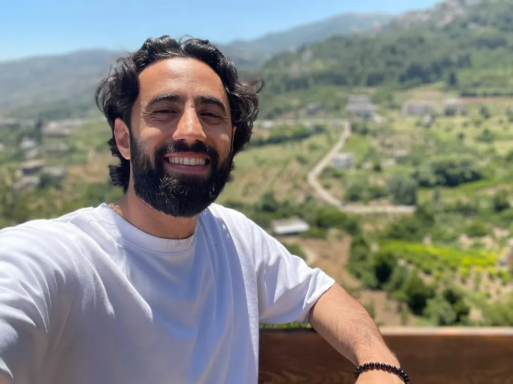 Dr. Ahmad Deeb outdoors, smiling, with green hills behind him
